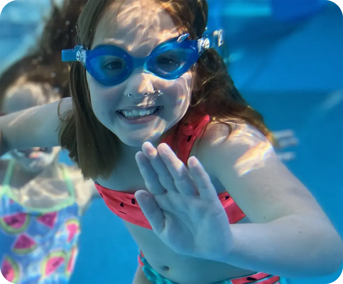 Child practicing one-on-one swim lesson with instructor at FINS Swim School.
