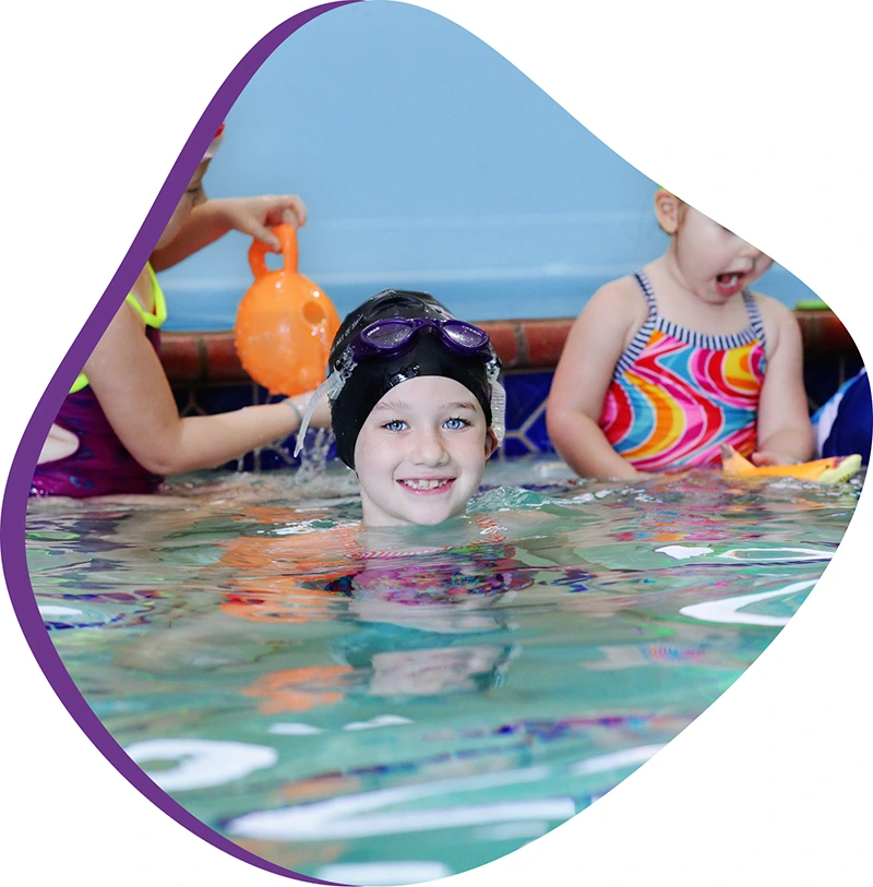 Children celebrating a birthday pool party at the FINS Swim School indoor pool. 