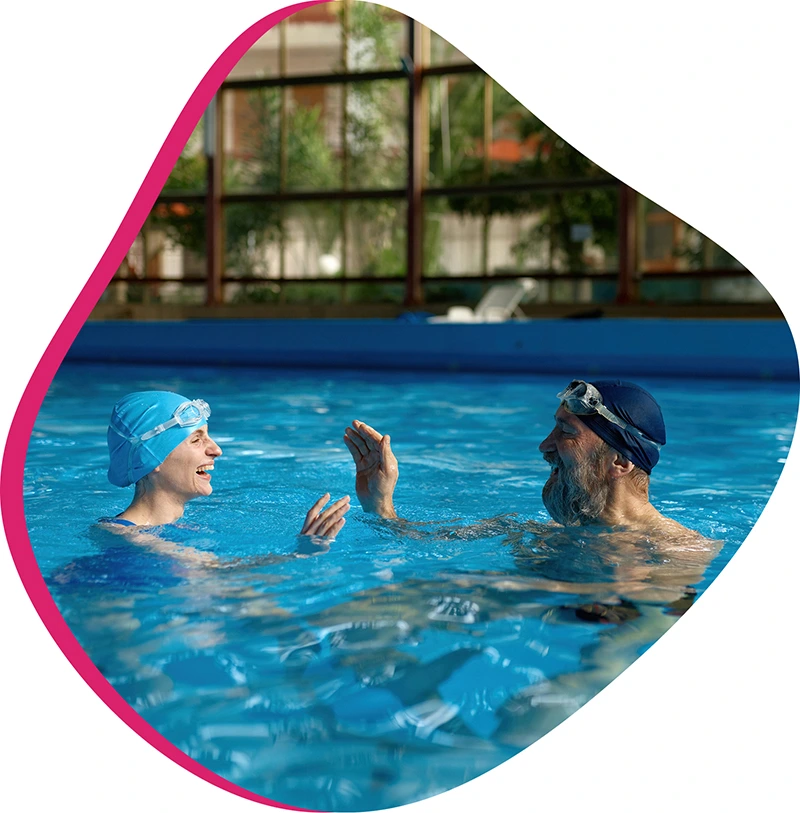 An adult student receiving personalized feedback from a swim instructor during a private session in a heated indoor pool.