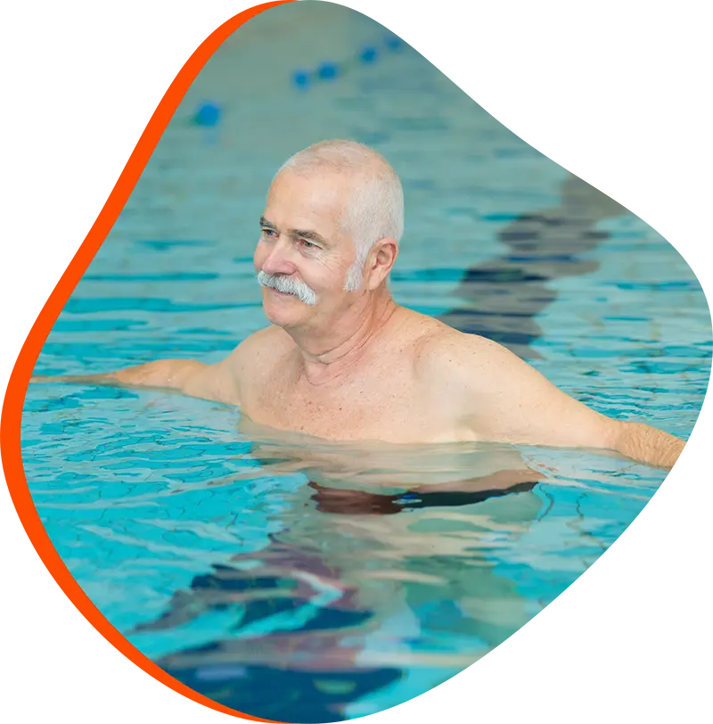 Adult swimmer practicing freestyle with a FINS instructor in a heated indoor pool at FINS Grand Parkway.