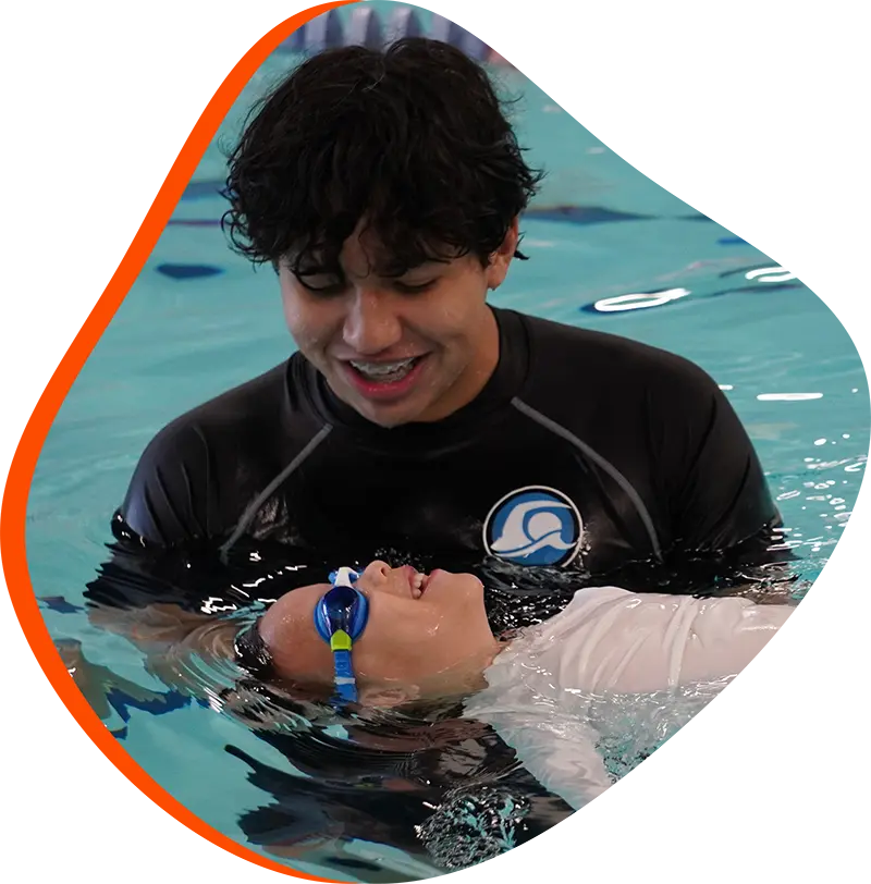A young swimmer practicing stroke technique with a professional instructor at FINS Grand Parkway.